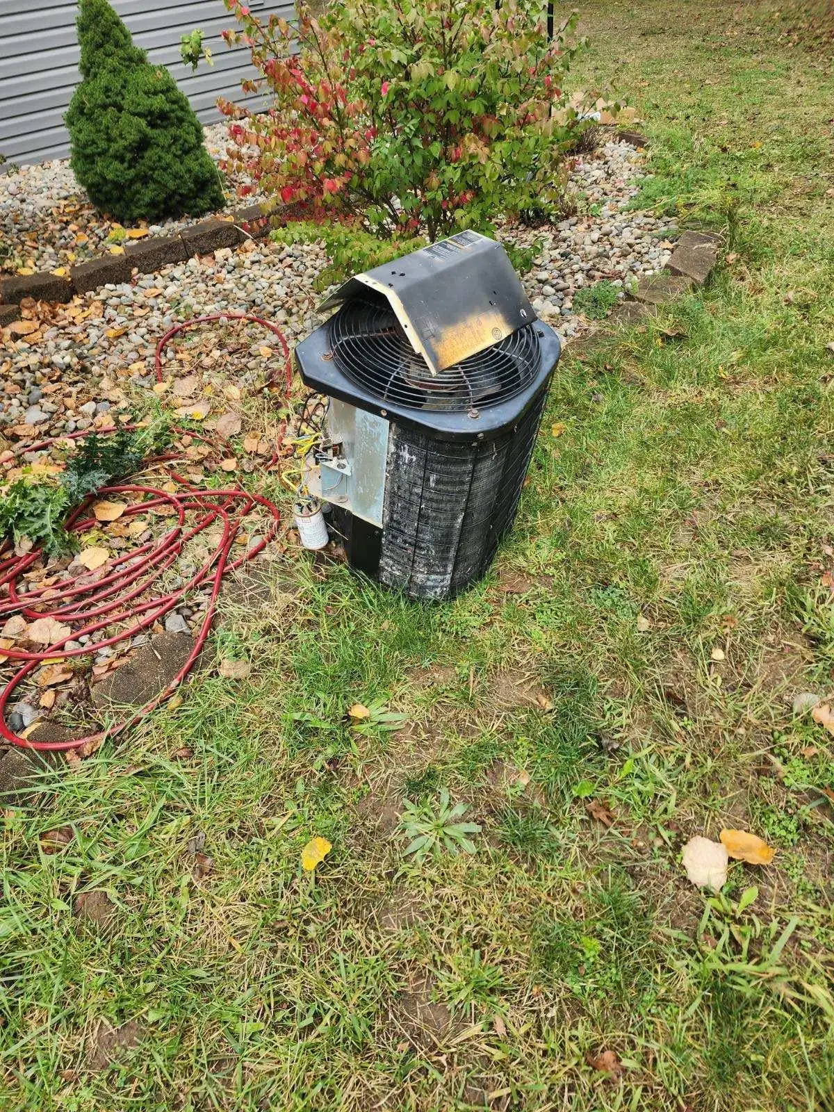 Damaged outdoor AC condenser unit being diagnosed by Great Lakes Comfort in Howell MI